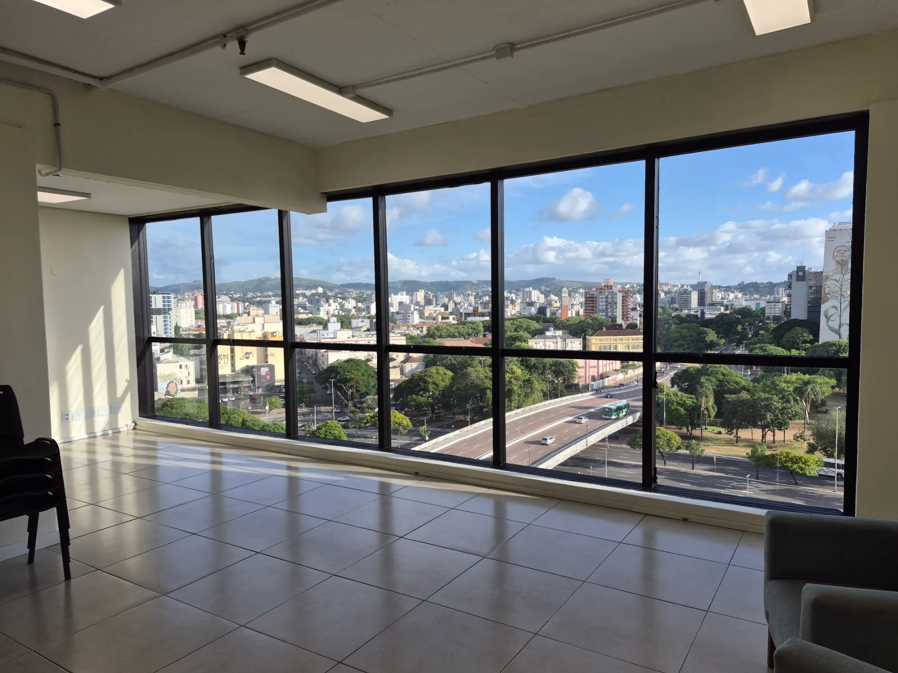 Sala da Travessia em Porto Alegre, vazia, com janela panorâmica para a cidade